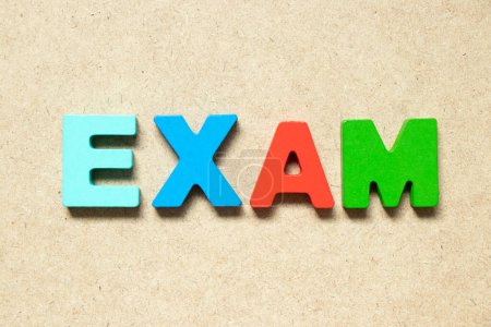 Color alphabet letter in word exam on wood background
