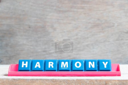 Téléchargez les photos : Lettre alphabet carrelage avec mot harmonie en rack de couleur rouge sur fond de bois - en image libre de droit