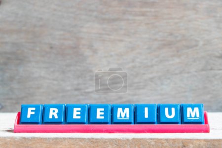 Téléchargez les photos : Lettre alphabet carrelage avec mot freemium en rack de couleur rouge sur fond bois - en image libre de droit