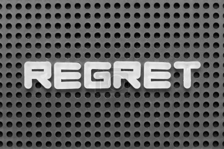 Téléchargez les photos : Lettre alphabet blanc dans le regret mot sur fond pegboard noir - en image libre de droit