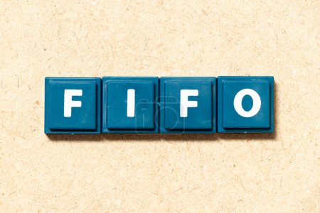 Téléchargez les photos : Lettre alphabet carrelage en mot FIFO (Abréviation du premier entré premier sorti) sur fond bois - en image libre de droit