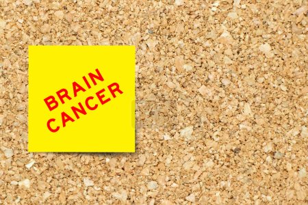 Téléchargez les photos : Papier de note jaune avec mot cancer du cerveau sur fond de carton de liège avec espace de copie - en image libre de droit