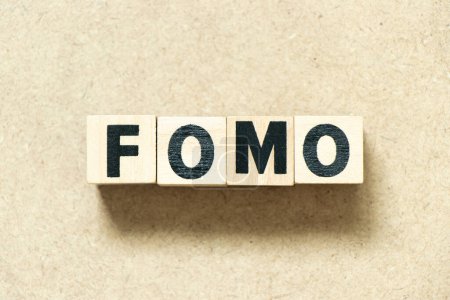 Alphabet letter block in word FOMO (abbreviation of fear of missing out) on wood background