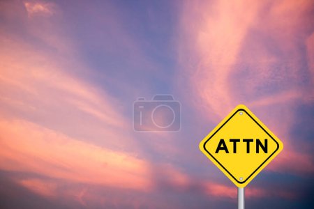 Yellow transportation sign with word ATTN (Abbreviation of attention) on violet color sky background