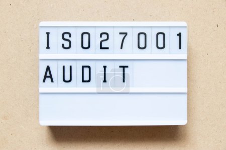 Leuchtkasten mit Wort ISO 270001 Audit auf Holzhintergrund