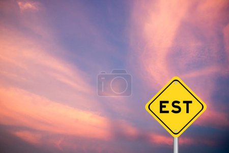 Señal amarilla de transporte con palabra EST (abreviatura de zona horaria establecida, estimada, oriental, etiqueta de secuencia expresada) sobre fondo celeste de color violeta