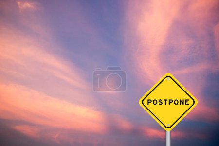 Yellow transportation sign with word postpone on violet color sky background