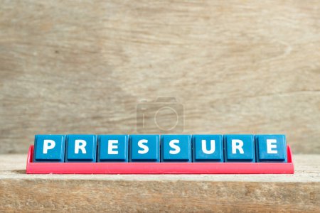 Tile letter on red rack in word pressure on wood background