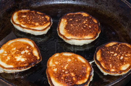 The cook is frying pancakes in a frying pan