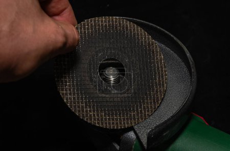 Photo for Master installs a disc on an angle grinder - Royalty Free Image