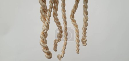 Photo for Organic silk, strands of fine silk yarn. Bundle of thin, natural-colored silk yarn, tightly twisted together and arranged in a bundle on a white background. Yarn for knit and crochet. Materials for handicrafts. - Royalty Free Image