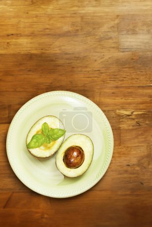 Photo for Ripe avocado slices arranged on a green plate, garnished with aromatic basil - Royalty Free Image