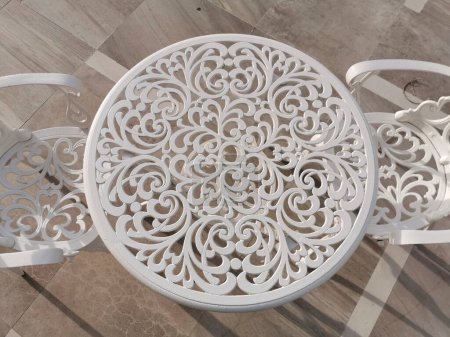Photo for White wrought iron table and chair with floral motifs on terrace at dawn. High quality photo - Royalty Free Image