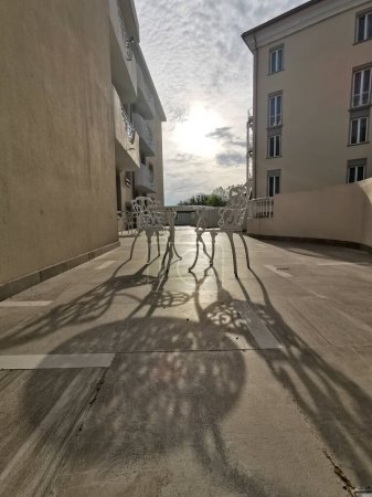 Foto de Mesa y silla de hierro forjado blanco con motivos florales en la terraza al amanecer. Foto de alta calidad - Imagen libre de derechos