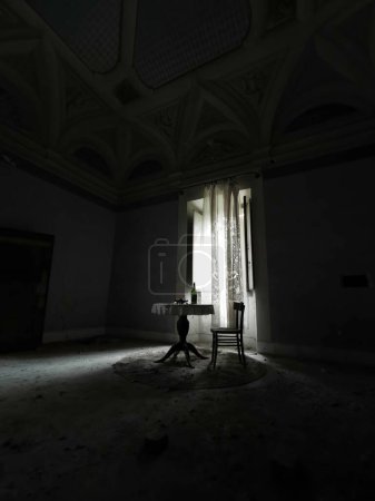Foto de Habitación débilmente iluminada con mesa y sillas en casa abandonada. Foto de alta calidad - Imagen libre de derechos