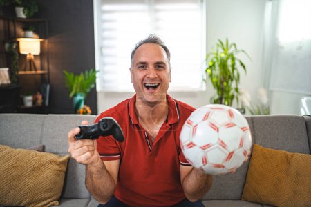 Foto de Edad Media hombre caucásico jugando fútbol videojuego en casa. - Imagen libre de derechos
