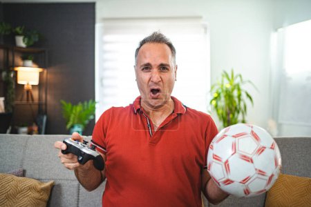 Photo for Worried middle aged man playing soccer video game at home. - Royalty Free Image
