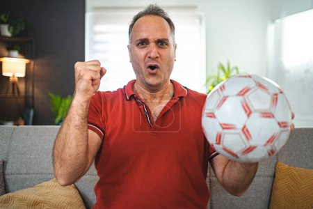 Photo for Worried middle aged man watching soccer game at home. - Royalty Free Image