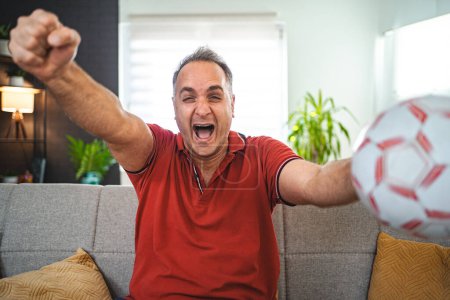 Téléchargez les photos : Homme d'âge moyen excité regardant le match de football à la maison. - en image libre de droit