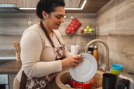 Téléchargez les photos : Femme lave la vaisselle dans la cuisine. - en image libre de droit