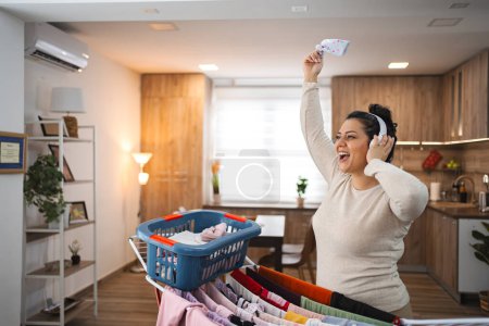 Foto de Mujer cantando mientras cuelga la ropa en el tendedero en casa. - Imagen libre de derechos