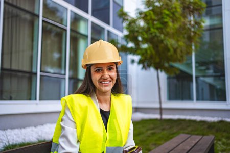 Photo for Smiling female safety engineer sitting on a bench. - Royalty Free Image