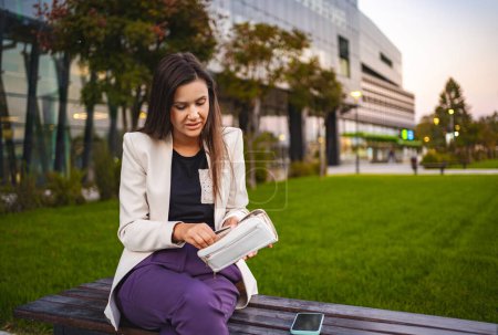 Photo for Businesswoman sitting at the park after work checking her wallet. - Royalty Free Image