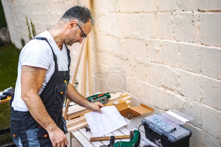Foto de Maduro carpintero macho trabajando con tablón de madera al aire libre. - Imagen libre de derechos