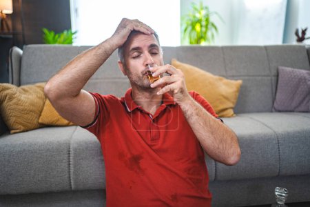 Photo for Mature man sitting on the floor and drinking alcohol. - Royalty Free Image