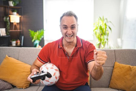 Téléchargez les photos : Moyen Age homme caucasien jouer au football jeu vidéo à la maison. - en image libre de droit