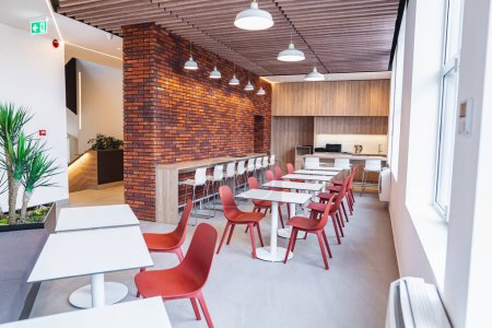 L'image présente un cadre typique de restaurant avec des tables et des chaises soigneusement disposées contre un mur de briques texturées. L'intérieur dégage une ambiance chaleureuse et accueillante parfaite pour dîner.
