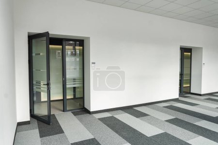 Büroflächen ohne Möbel oder Dekoration, mit nur zwei Türen und schwarz-weiß kariertem Boden. Die Türen sind geschlossen, was zu unbekannten Zielen führt, während der Fußboden eine geometrische
