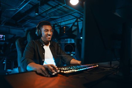 Téléchargez les photos : Un homme en casque est assis sur un ordinateur et réagit activement au jeu. Photo de haute qualité - en image libre de droit