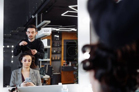 Téléchargez les photos : Le maître fait de la coiffure dans un salon de beauté. Une jeune femme se prépare pour un rendez-vous. Photo de haute qualité - en image libre de droit