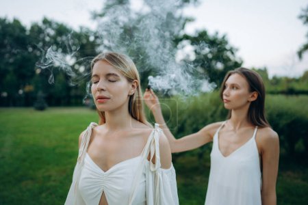 Téléchargez les photos : Une jeune femme pratique la méditation dans la nature. Méditation avec fumée. Photo de haute qualité - en image libre de droit