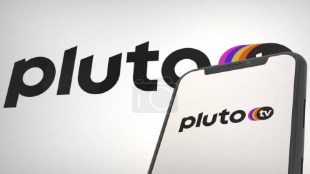Téléchargez les photos : Logo de l'application Pluton TV dans l'écran d'affichage mobile et l'éditorial de fond - en image libre de droit
