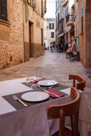 Conjunto de mesa de restaurante en la calle en Alcudia, Mallorca. Casco antiguo tradicional en España