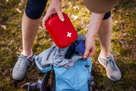 Woman taking out first aid kit from backpack. Prepared for health problems during hiking. Travel insurance for all eventualities