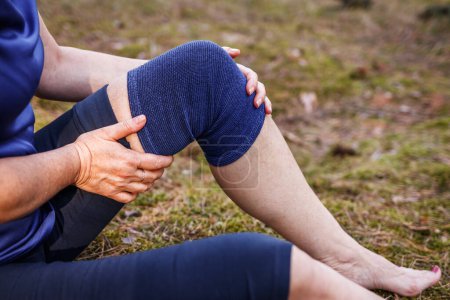 Wanderer legen beim Wandern elastische orthopädische Binden an. Frau spürt Schmerzen in Gelenk und Knie nach Verletzung. Erste Hilfe bei Bänder- oder Knieverstauchungen im Freien