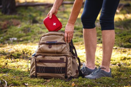 Hiker taking out first aid kit from backpack. Prepared for health problems during hiking. Travel insurance for all eventualities