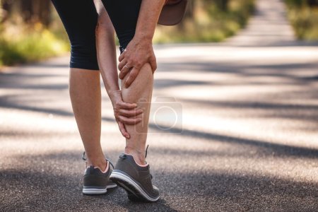 Mujer sintiendo dolor en las piernas durante el trote. Calambre muscular de la pantorrilla. Subestimar el ejercicio de calentamiento antes de correr