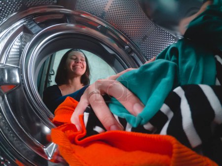 a woman loads a washing machine with dirty clothes