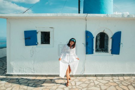 Photo for Beautiful woman in white dress near old greece church white with blue - Royalty Free Image