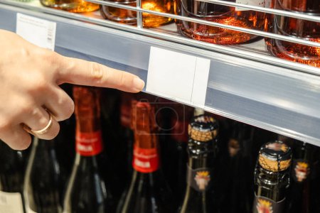 Female finger points to cost tag in supermarket