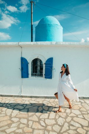 Photo for Beautiful woman in white dress near old greece church white with blue - Royalty Free Image