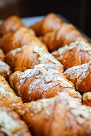 Photo for Sprinkle finished croissants on baking sheet with almond flakes - Royalty Free Image