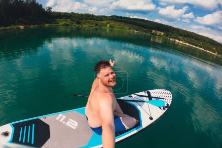 Foto de Feliz hombre toma selfie en supboard en el centro del lago - Imagen libre de derechos