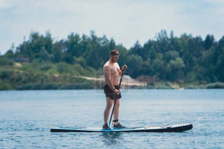 Foto de Hombre de pie en el supboard en el medio del lago actividades de agua de verano - Imagen libre de derechos