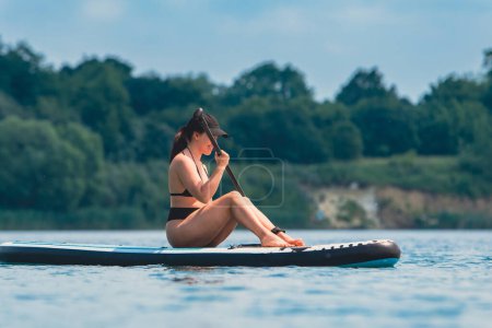 Foto de Atractiva mujer en traje de baño en supboard en el medio del lago - Imagen libre de derechos