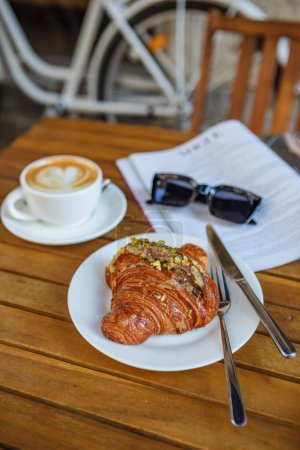 Téléchargez les photos : Petit déjeuner avec croissant, café et magazine au café - en image libre de droit